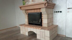 Kominek jest wyłożony kamieniem naturalnym, drewnem i płytkami ceramicznymi.