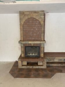 Kominek z kamienia naturalnego i płytek ceramicznych.