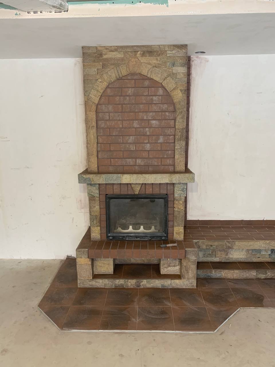 Kominek z kamienia naturalnego i płytek ceramicznych.