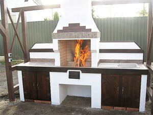 Grill ogrodowy jest otynkowany i pomalowany. Zawiera dekoracyjne elementy drewniane.